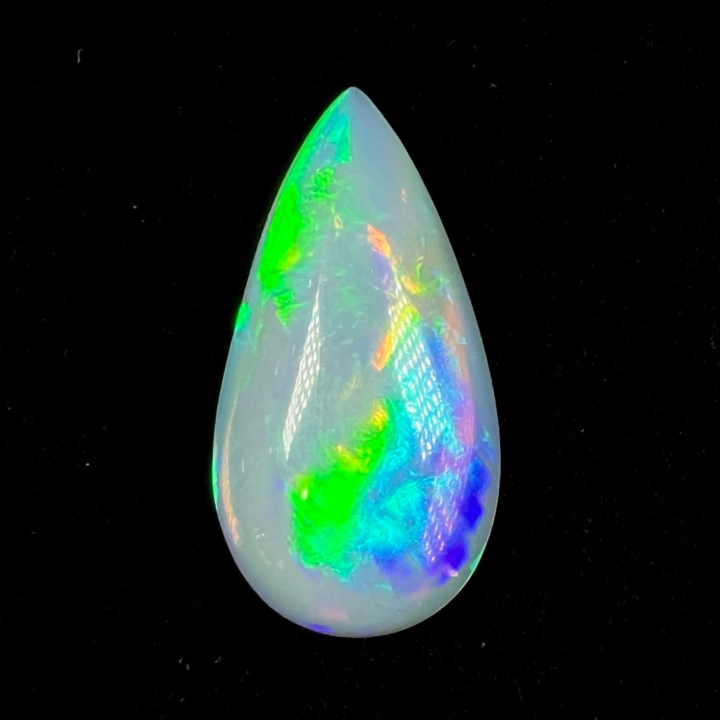 A pear shaped Ethiopian fire opal stone. The opal has green, blue, and purple color play.