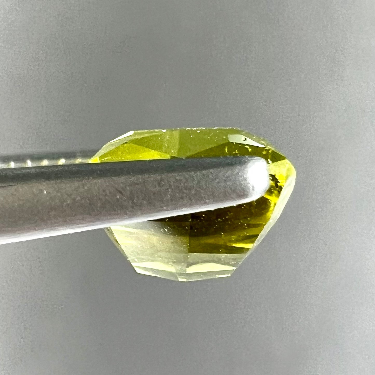 A loose, modified cushion cut greenish yellow chrysoberyl gemstone.