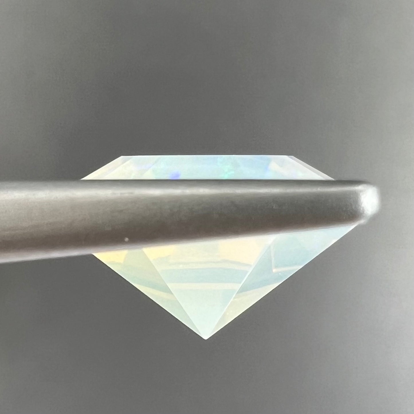 A loose, faceted octagon cut Mexican fire opal gemstone. The stone is a light yellow color with blue and green fire.