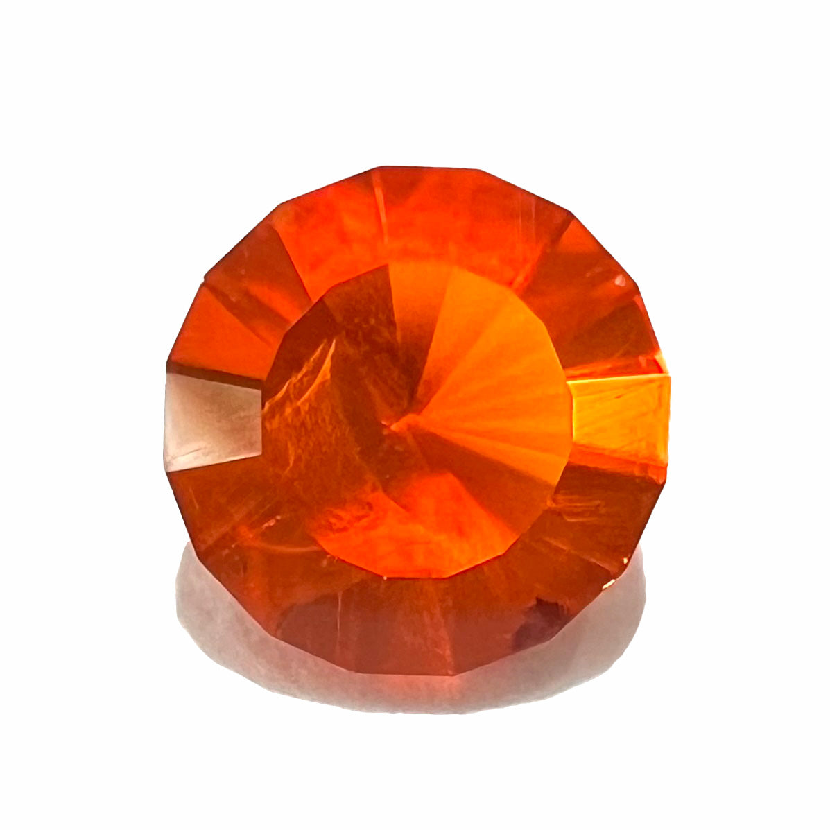 A faceted round cut natural Mexican fire opal stone. The stone is bright orange in color.