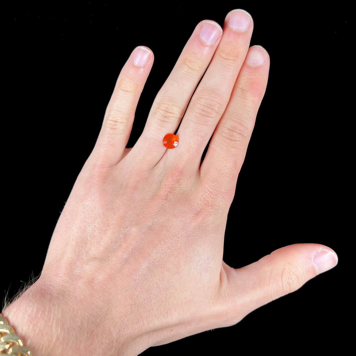 A faceted round cut natural fire opal from Mexico. The stone is a bright orange color.