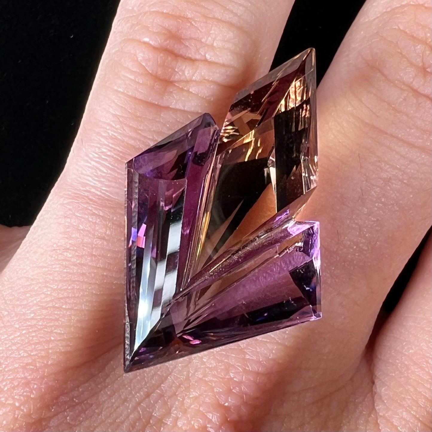 A loose, faceted fantasy cut ametrine gemstone cut by famous carver, Arthur Lee Anderson.