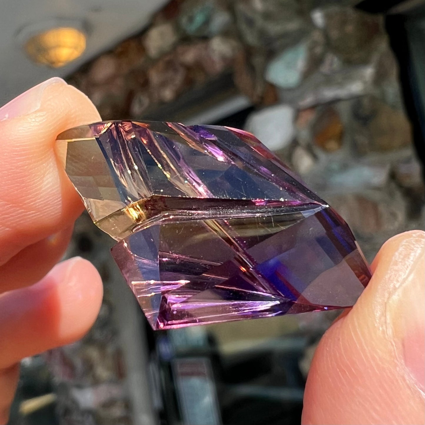 A loose, faceted fantasy cut ametrine gemstone cut by famous carver, Arthur Lee Anderson.