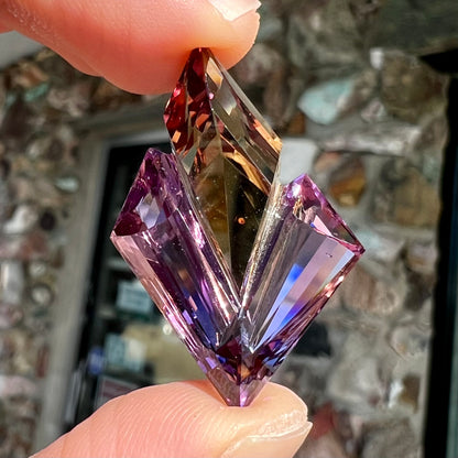 A loose, faceted fantasy cut ametrine gemstone cut by famous carver, Arthur Lee Anderson.