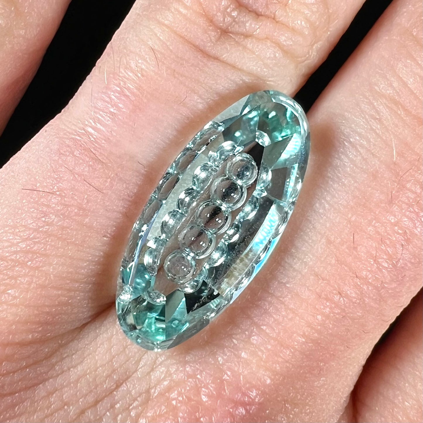 An oval fantasy cut greenish blue aquamarine stone cut by gem carver, Arthur Lee Anderson.