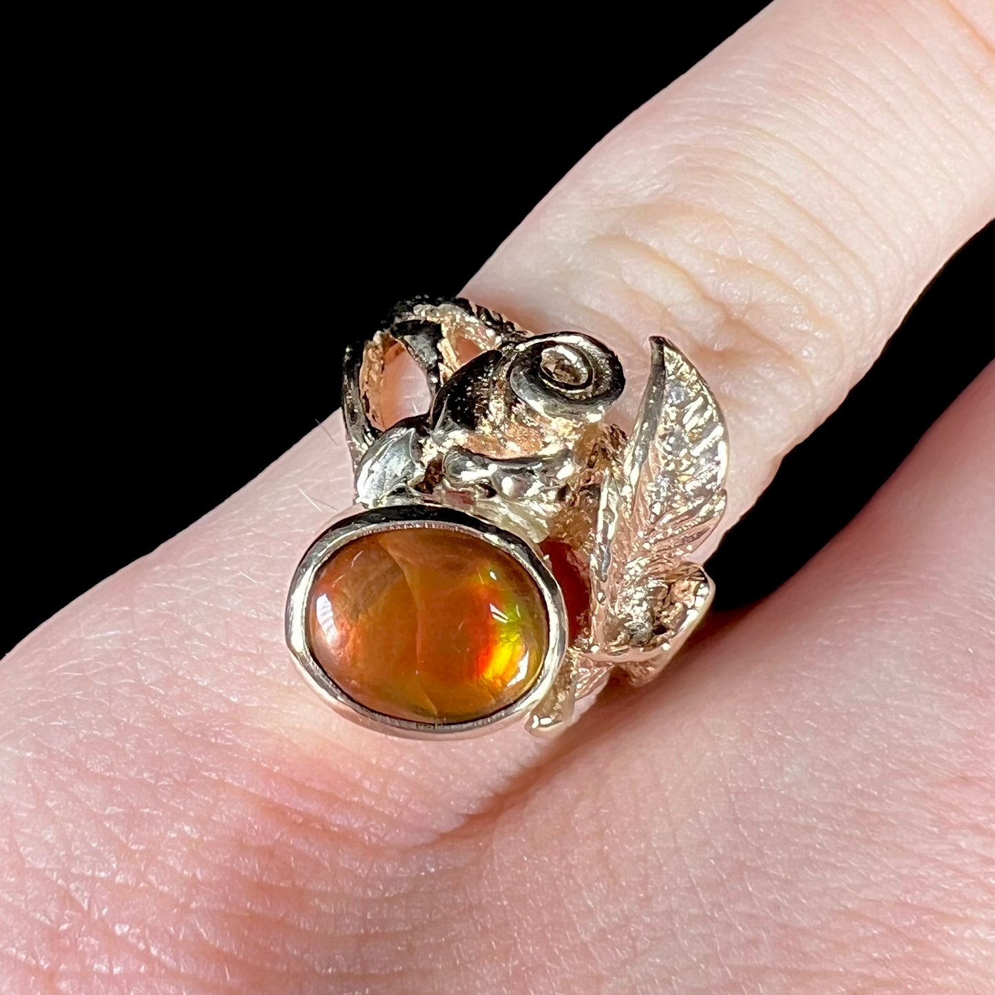 A ladies' yellow gold flower style ring set with an oval cabochon cut fire agate and diamond accents.