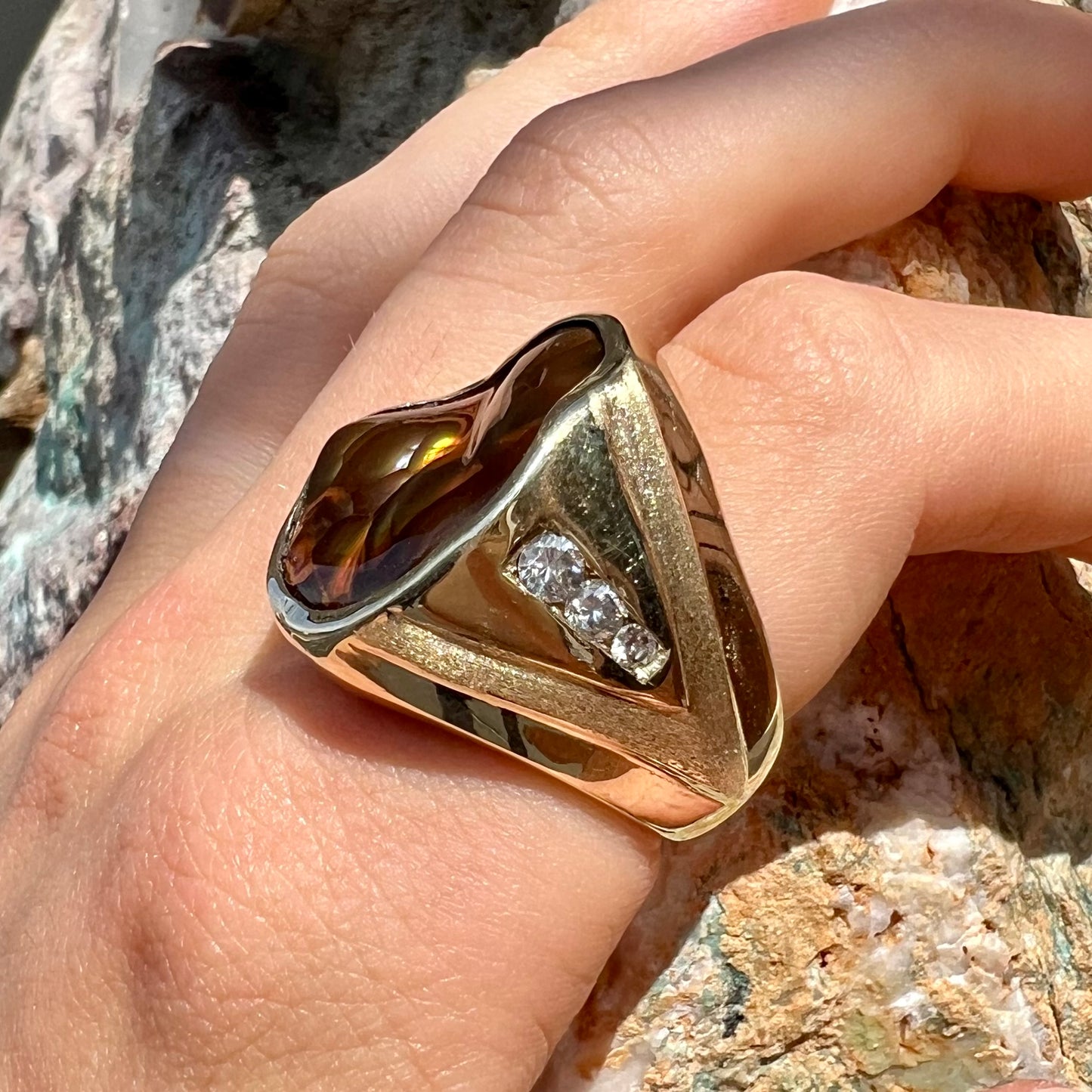 A men's heavy yellow gold ring set with a Mexican fire agate stone and three round brilliant cut diamond accents.