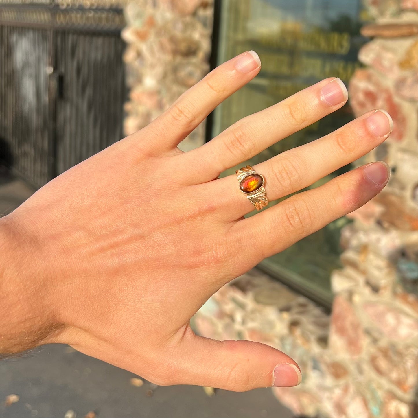 A unisex oval cabochon cut fire agate ring cast in yellow gold. The stone flashes green and red colors.