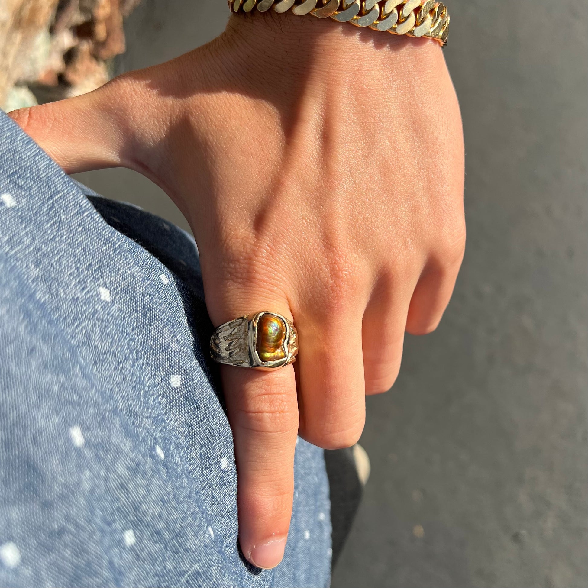 A man's yellow gold solitaire ring set with a freeform shaped Mexican fire agate stone.  The stone has a purple bull's eye pattern.