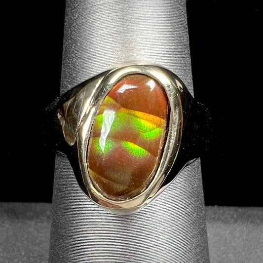 A yellow gold unisex Mexican fire agate solitaire ring.  The stone exhibits a snakeskin pattern with green, yellow, orange, and blue colors.