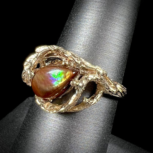A ladies' organic style yellow gold ring set with a pear shaped cabochon cut Mexican fire agate.  The stone shines green and purple.