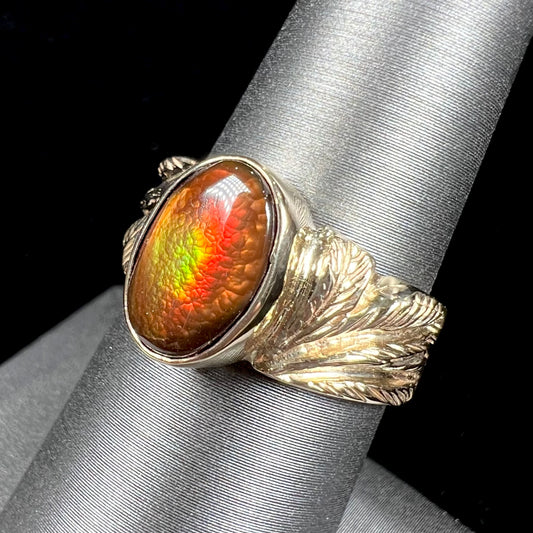 A unisex oval cabochon cut fire agate ring cast in yellow gold.  The stone flashes green and red colors.
