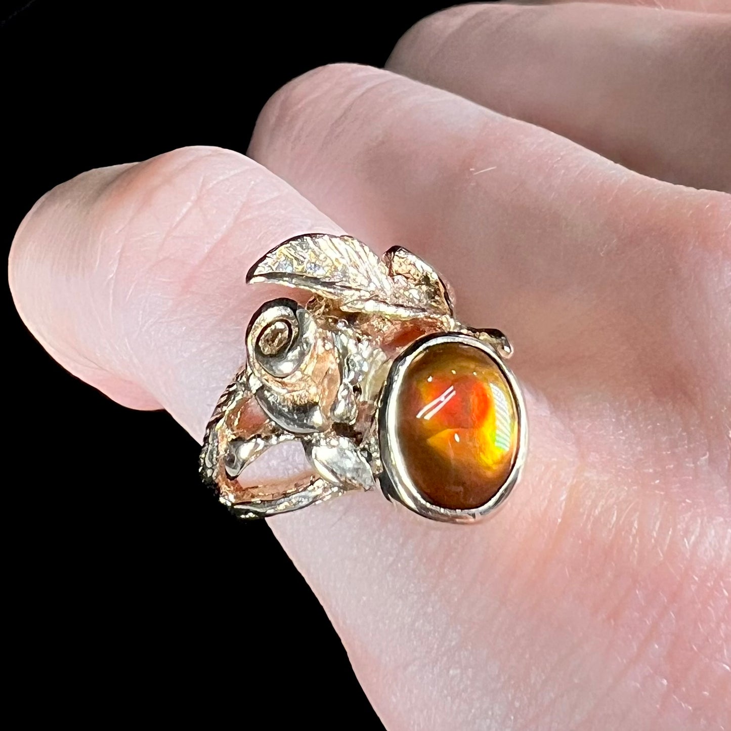 A ladies' yellow gold flower style ring set with an oval cabochon cut fire agate and diamond accents.