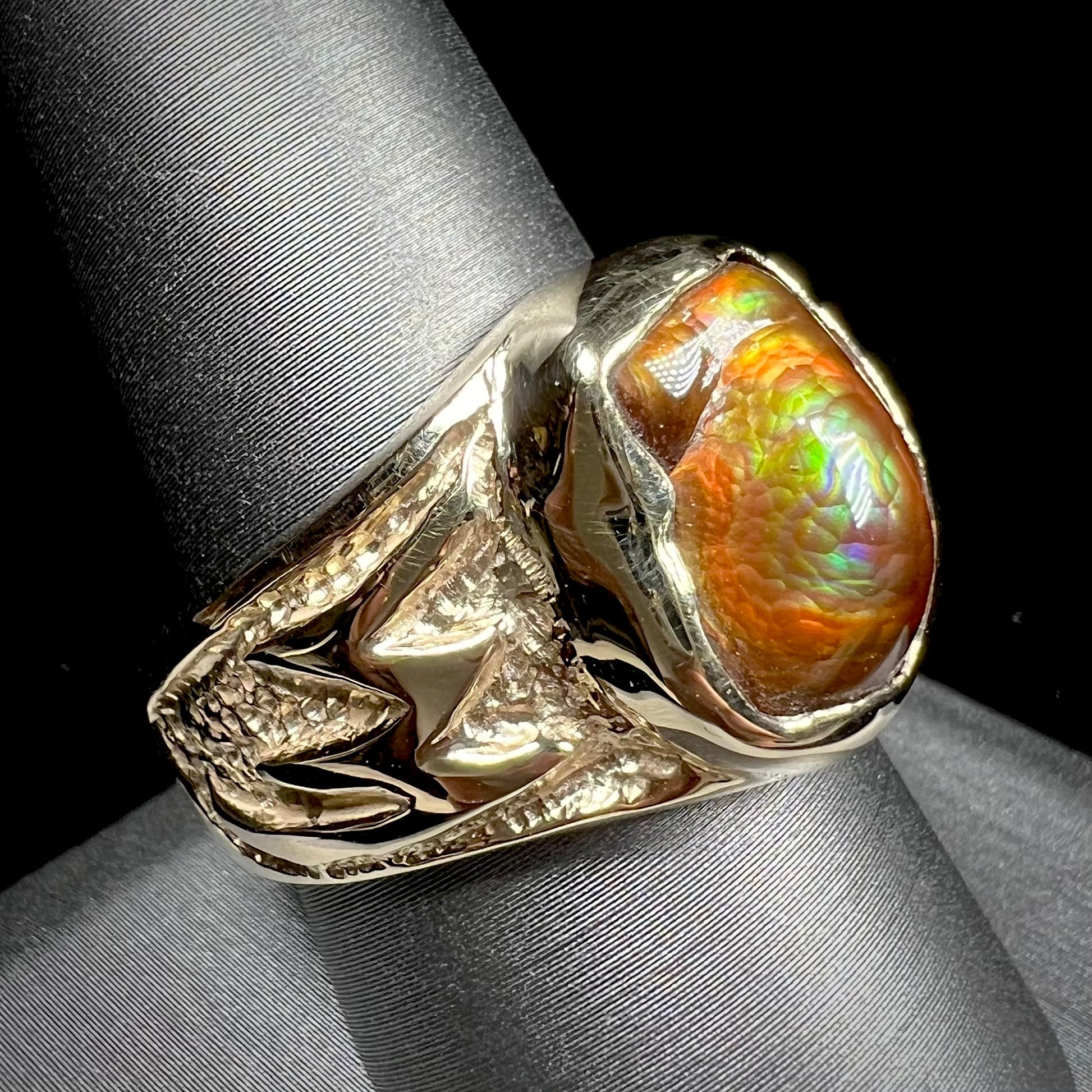 A man's yellow gold solitaire ring set with a freeform shaped Mexican fire agate stone.  The stone has a purple bull's eye pattern.