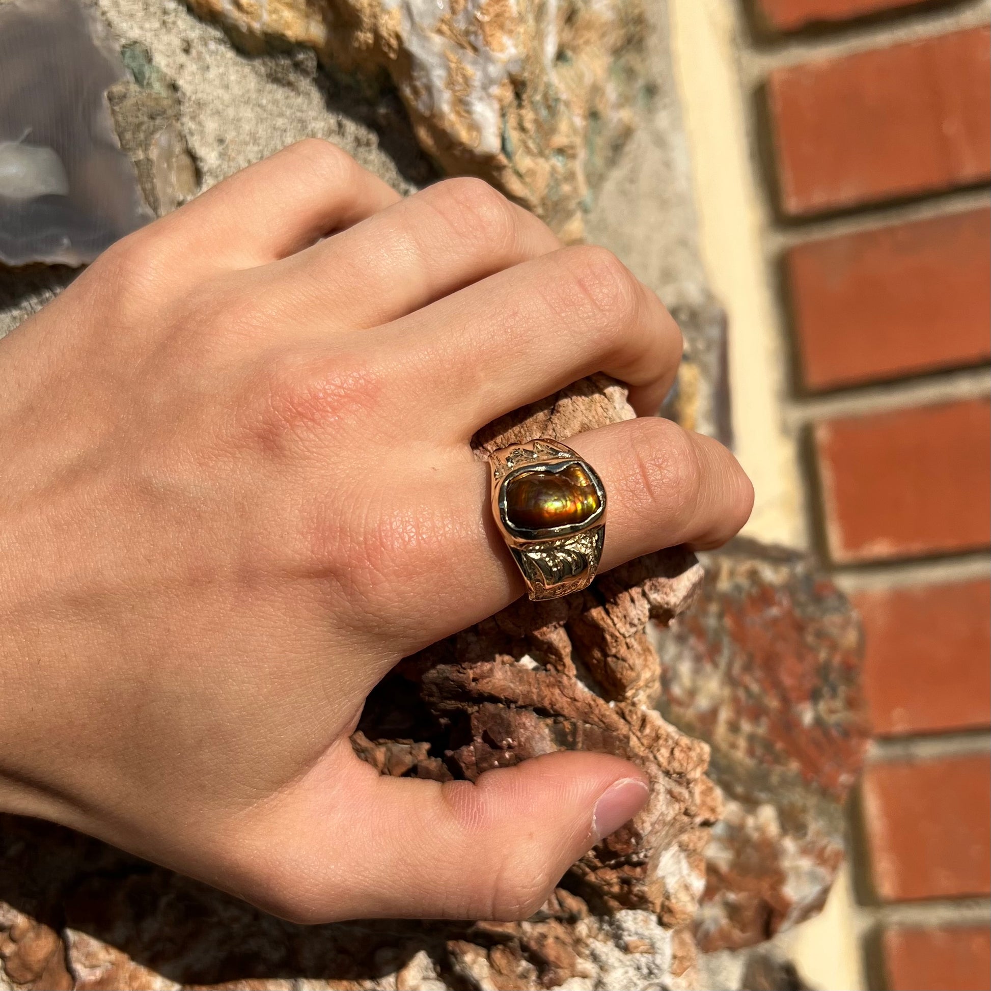 A man's yellow gold solitaire ring set with a freeform shaped Mexican fire agate stone.  The stone has a purple bull's eye pattern.