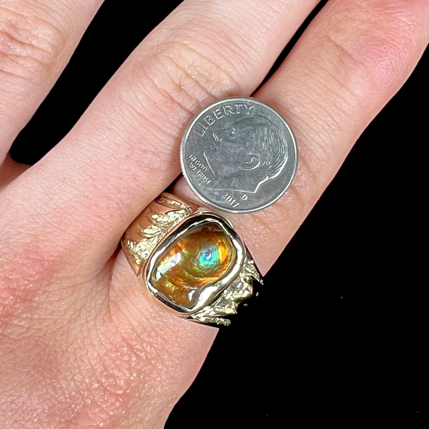 A man's yellow gold solitaire ring set with a freeform shaped Mexican fire agate stone.  The stone has a purple bull's eye pattern.