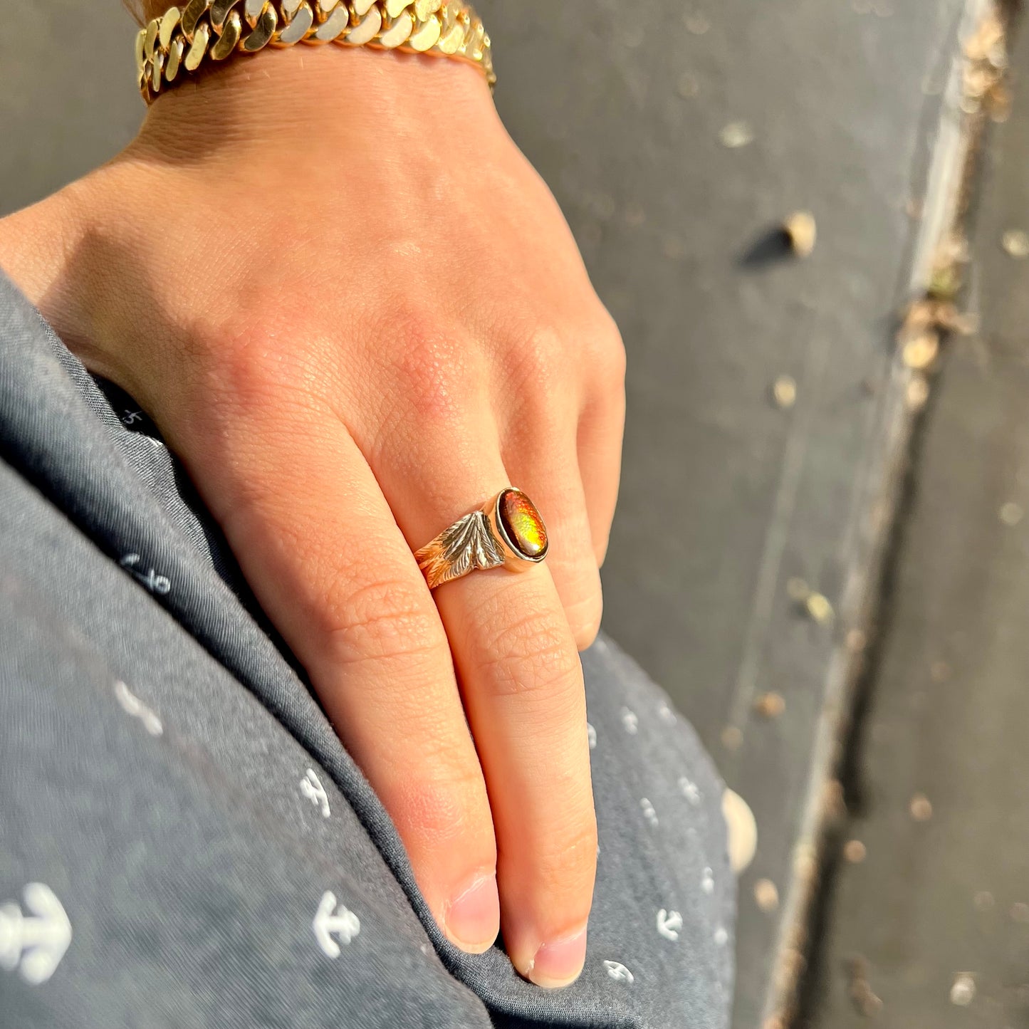 A unisex oval cabochon cut fire agate ring cast in yellow gold. The stone flashes green and red colors.