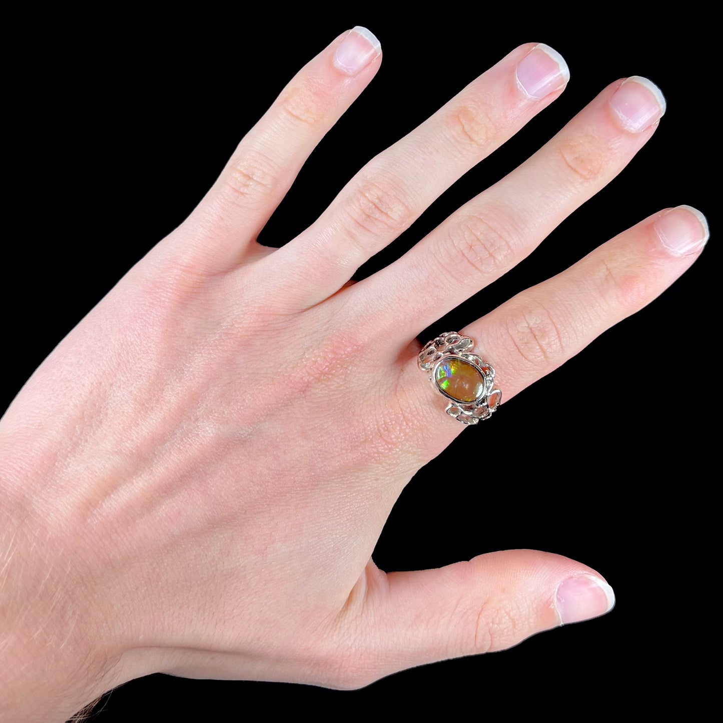 An organic-style white gold men's ring, bezel set with an oval cut Mexican fire agate stone.  The stone is green and purple.