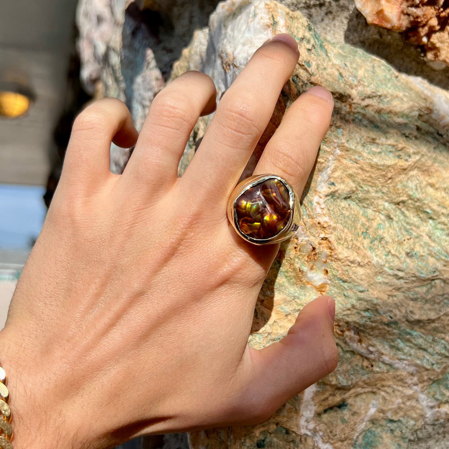 A men's heavy yellow gold ring set with a Mexican fire agate stone and three round brilliant cut diamond accents.