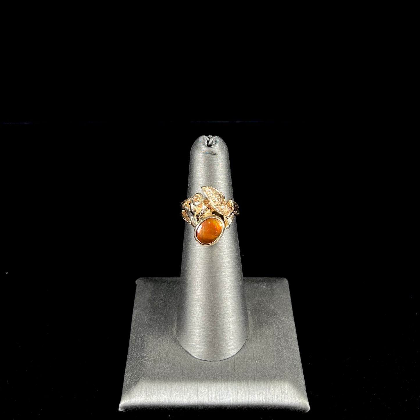 A ladies' yellow gold flower style ring set with an oval cabochon cut fire agate and diamond accents.