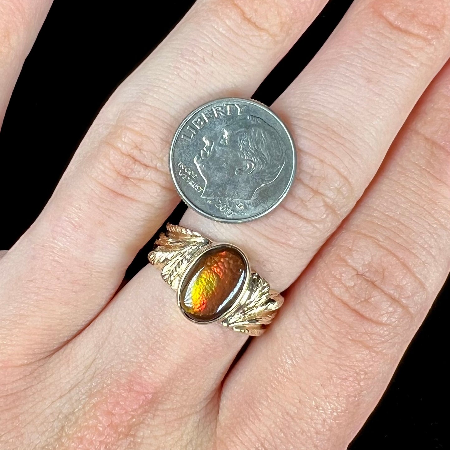 A unisex oval cabochon cut fire agate ring cast in yellow gold. The stone flashes green and red colors.