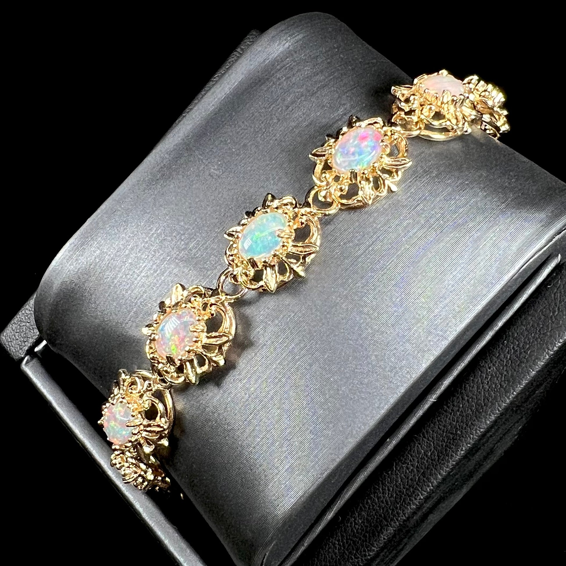 A ladies' yellow gold bracelet set with natural, oval cabochon cut white crystal opals.