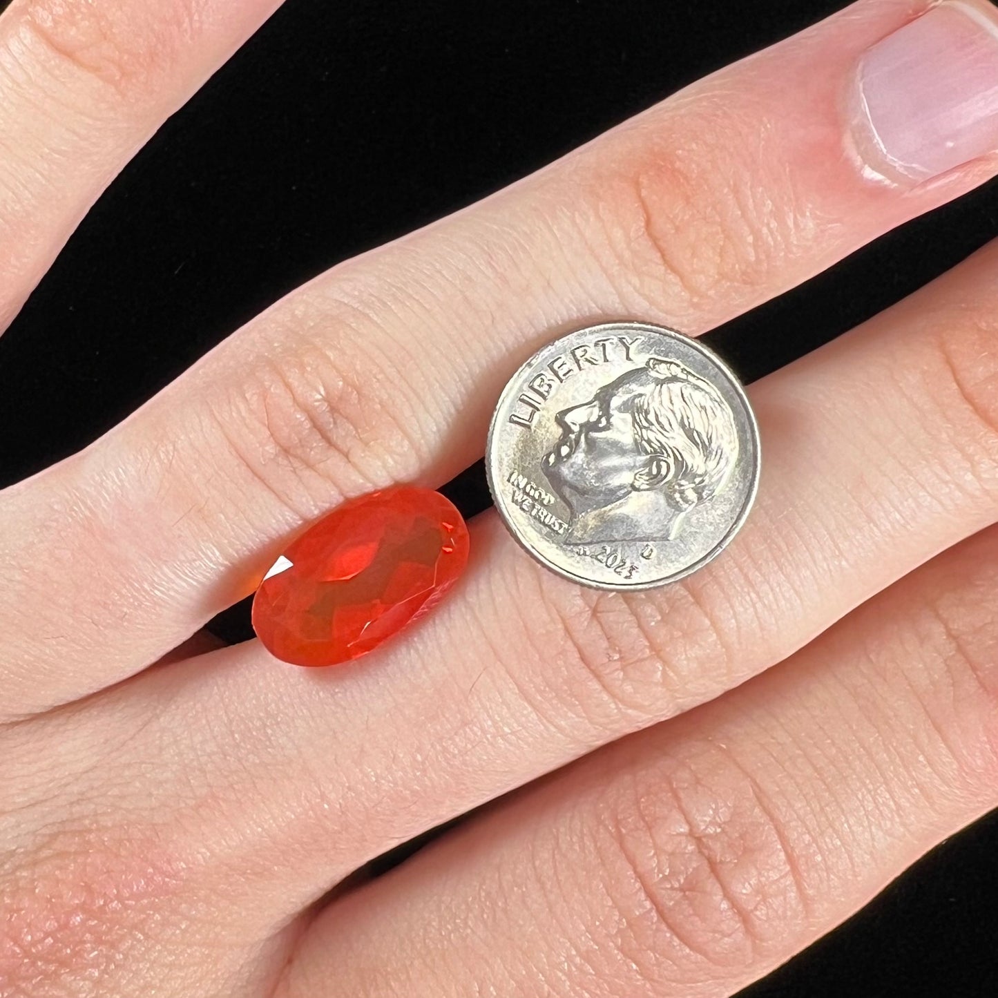 A loose, faceted oval cut Mexican fire opal stone. The stone is a bright orange color.
