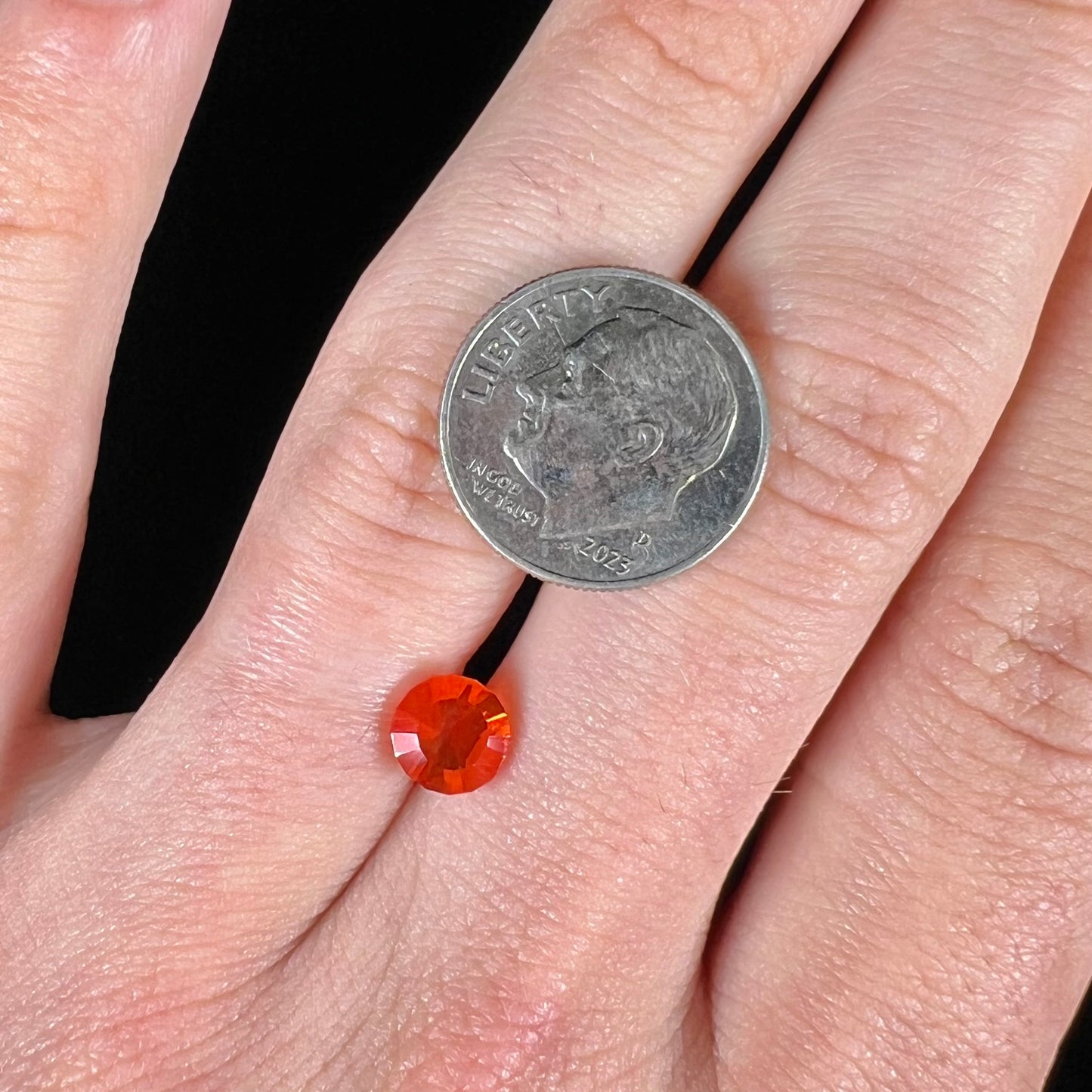 A faceted round cut natural Mexican fire opal stone. The stone is bright orange in color.