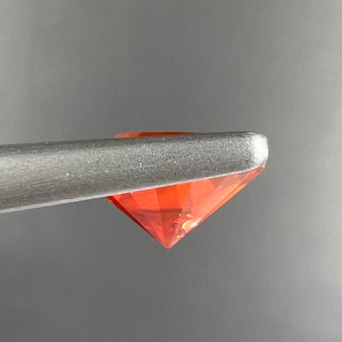 A faceted round cut natural fire opal from Mexico. The stone is a bright orange color.
