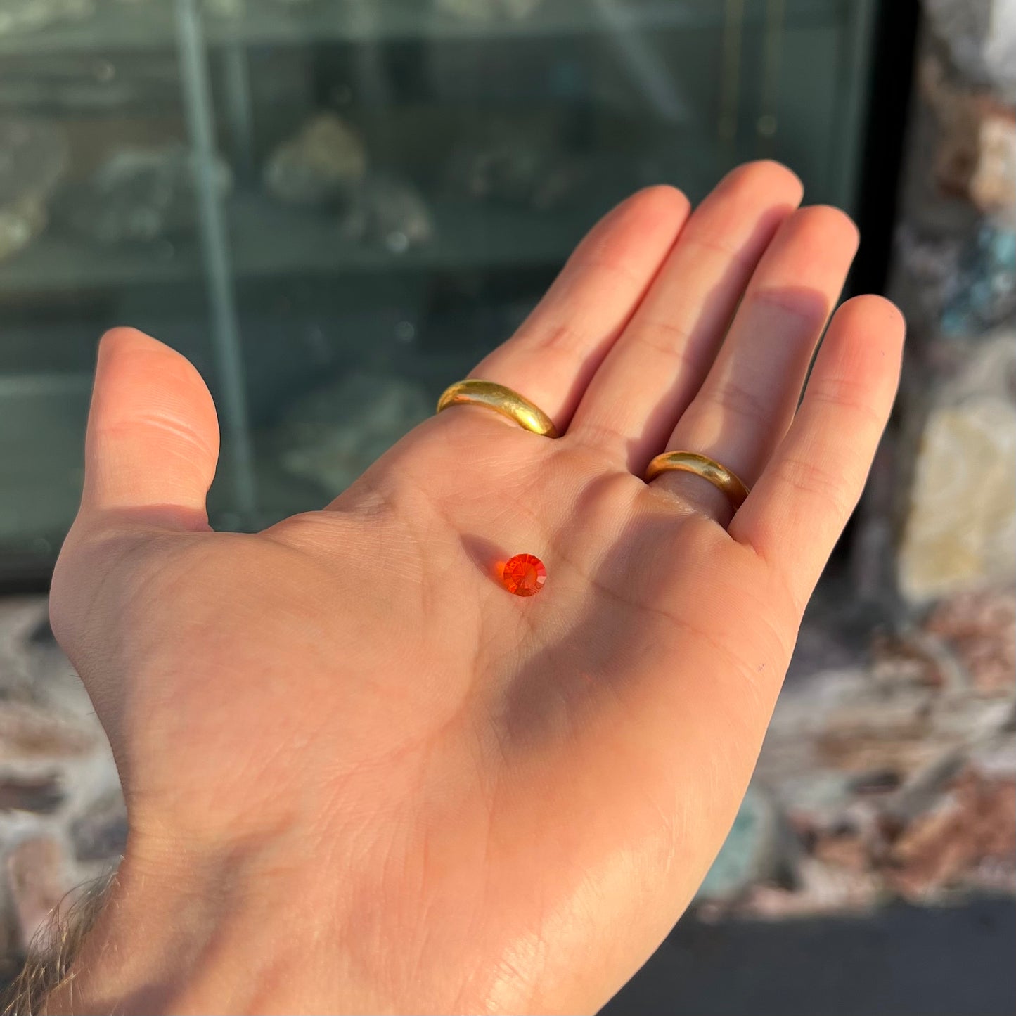 A faceted round cut natural Mexican fire opal stone. The stone is bright orange in color.