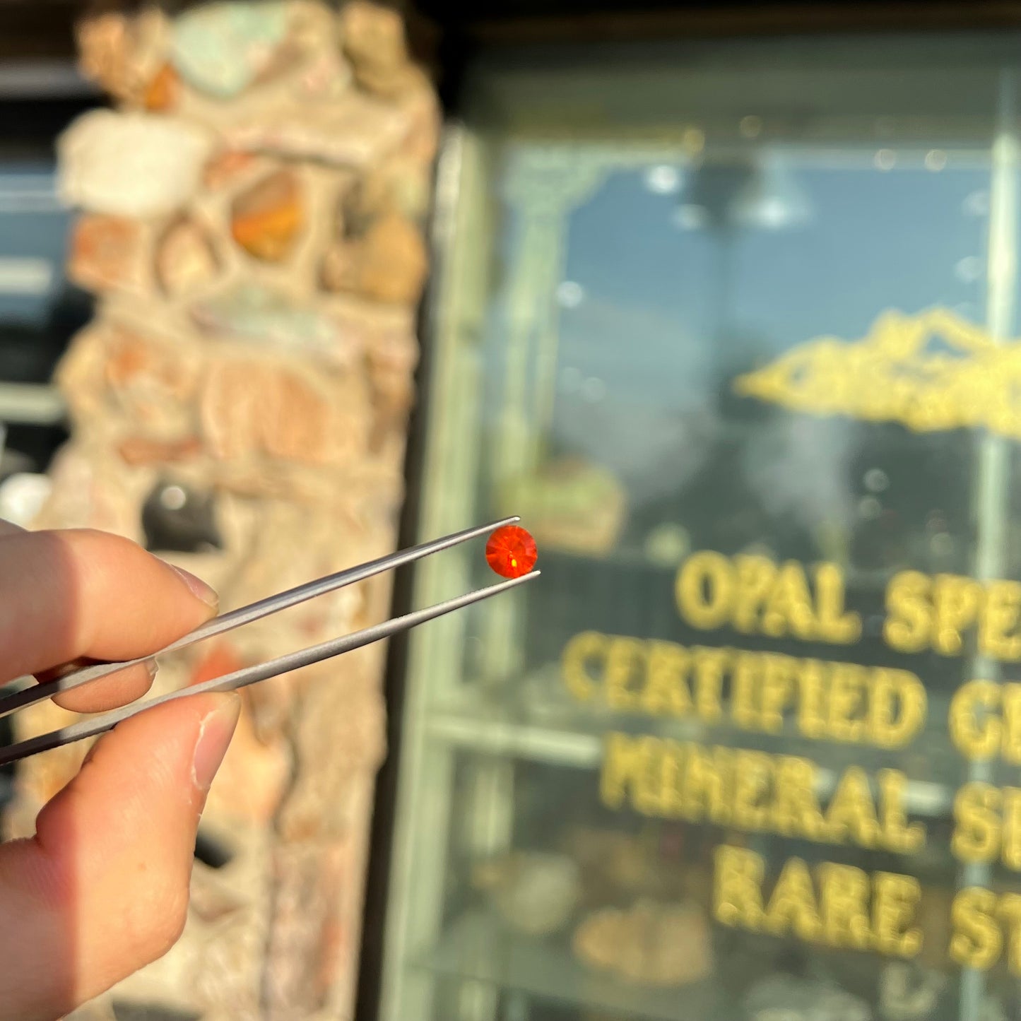A faceted round cut natural Mexican fire opal stone. The stone is bright orange in color.