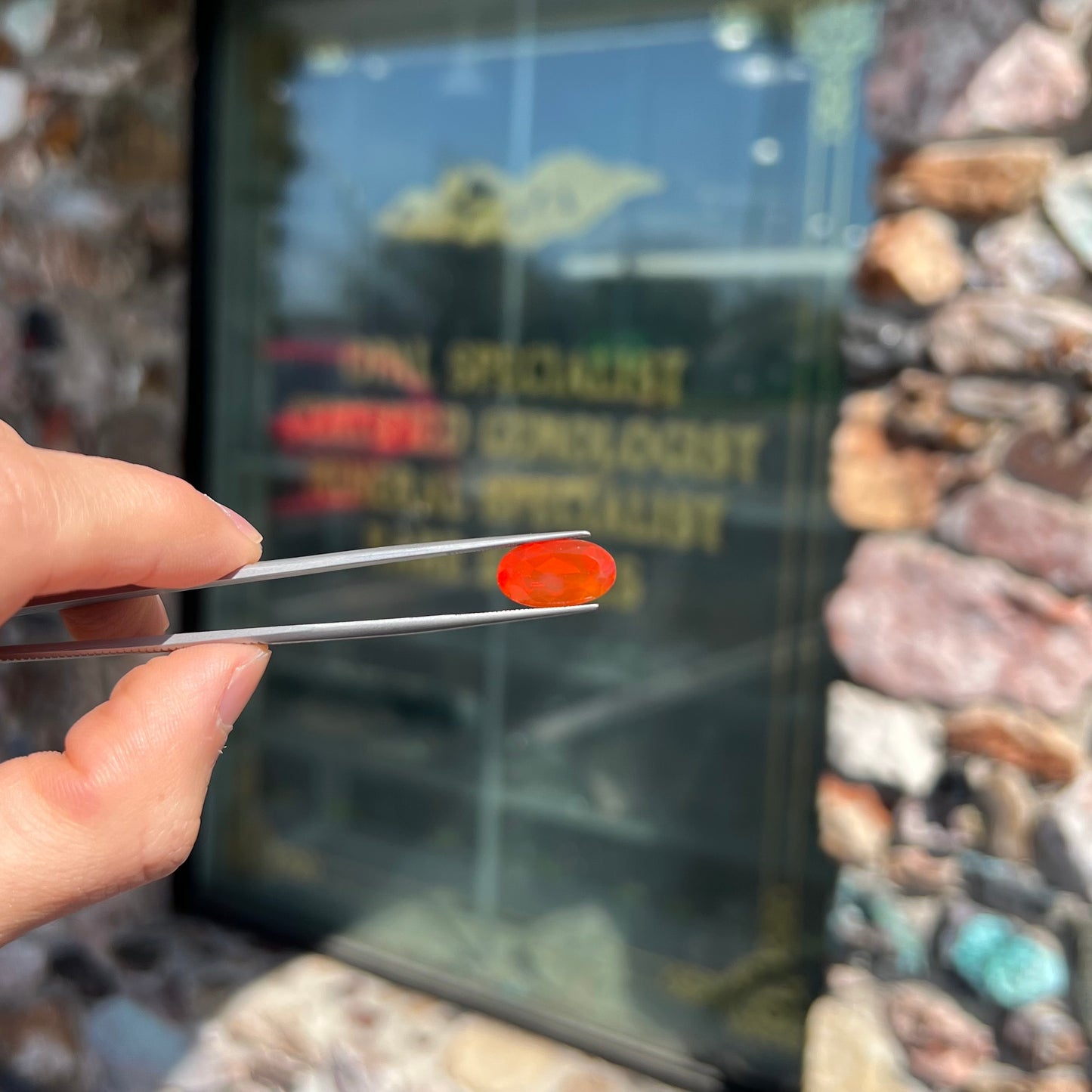 A loose, faceted oval cut Mexican fire opal stone. The stone is a bright orange color.