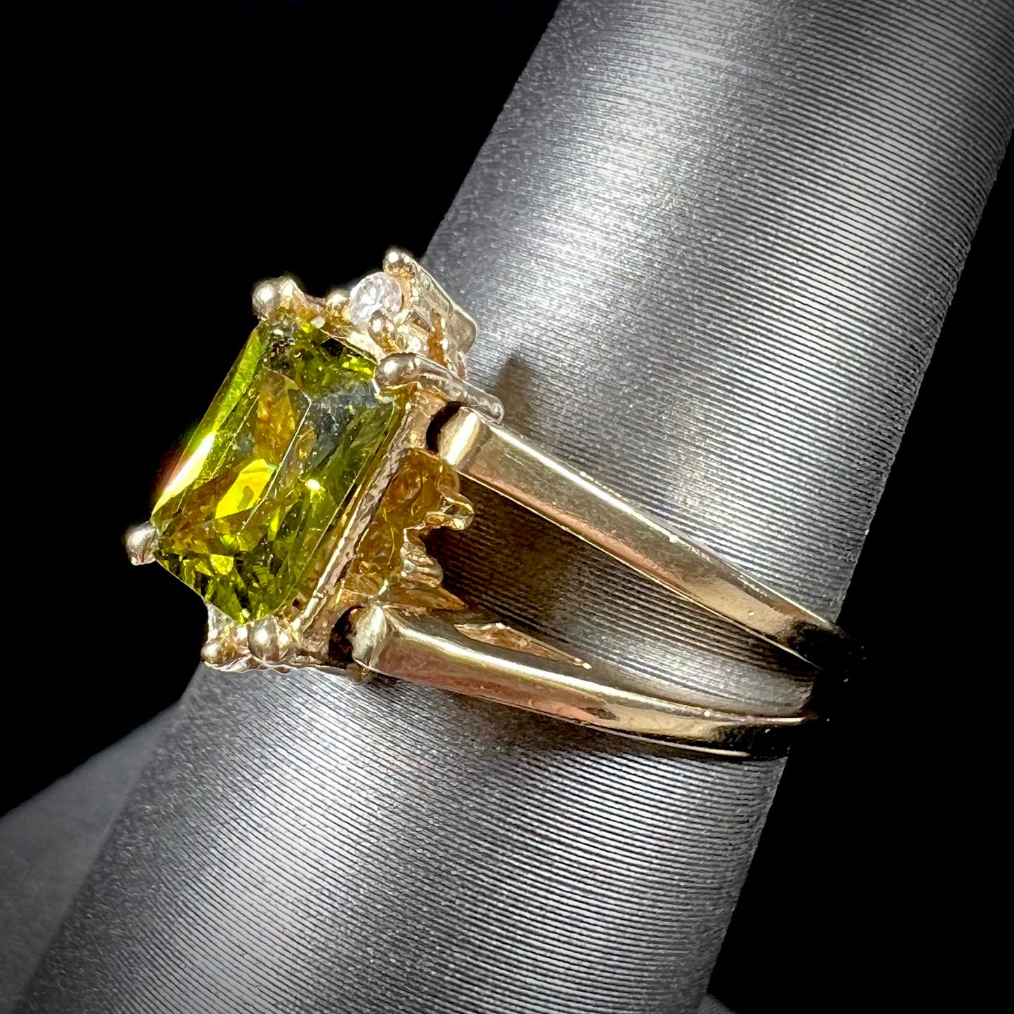 A yellow gold reversible gemstone flip ring. One side of the ring shows a green gemstone, the other shows a cluster of cubic zirconia.