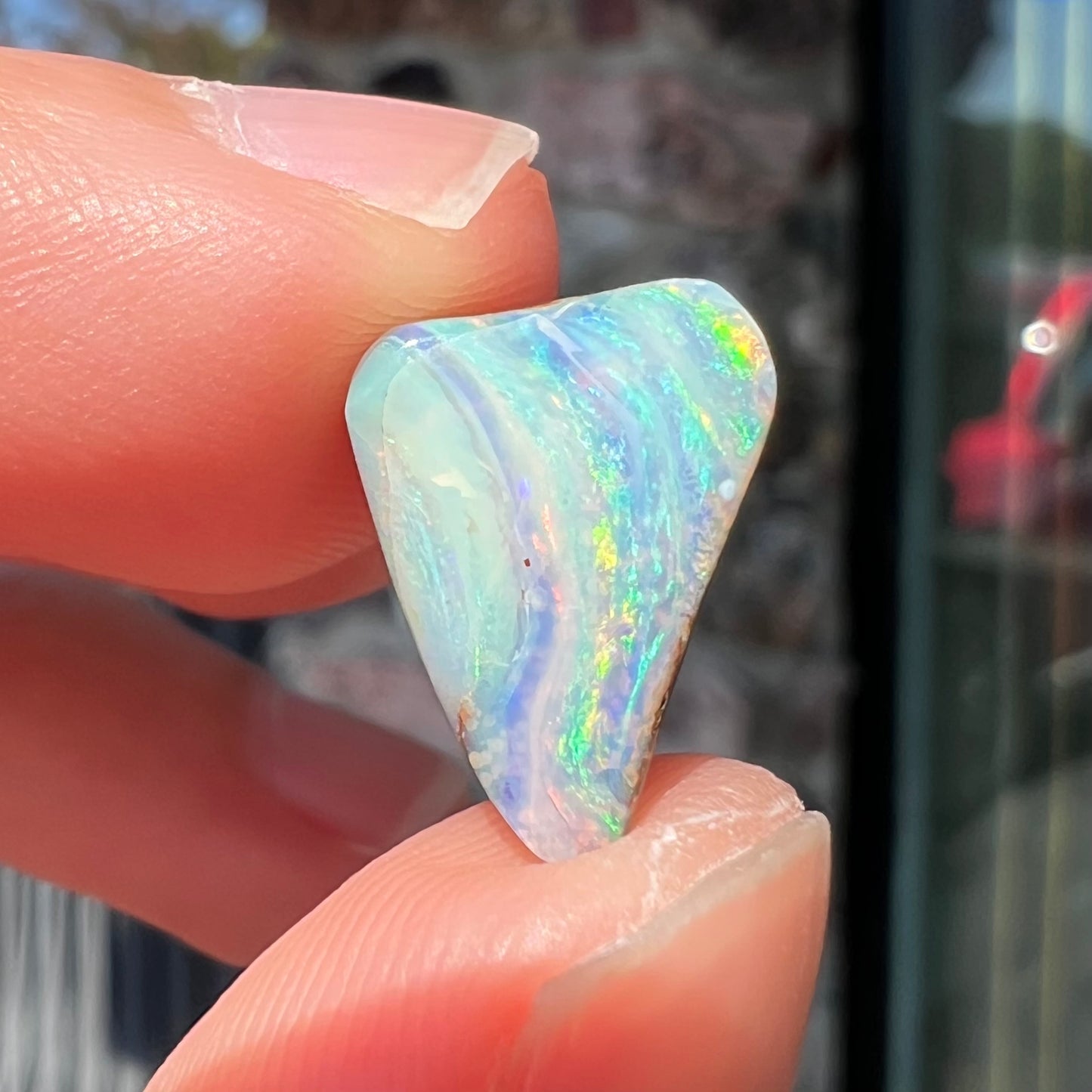 A loose, freeform boulder opal stone from Quilpie, Australia. The opal has a fissure inclusion.