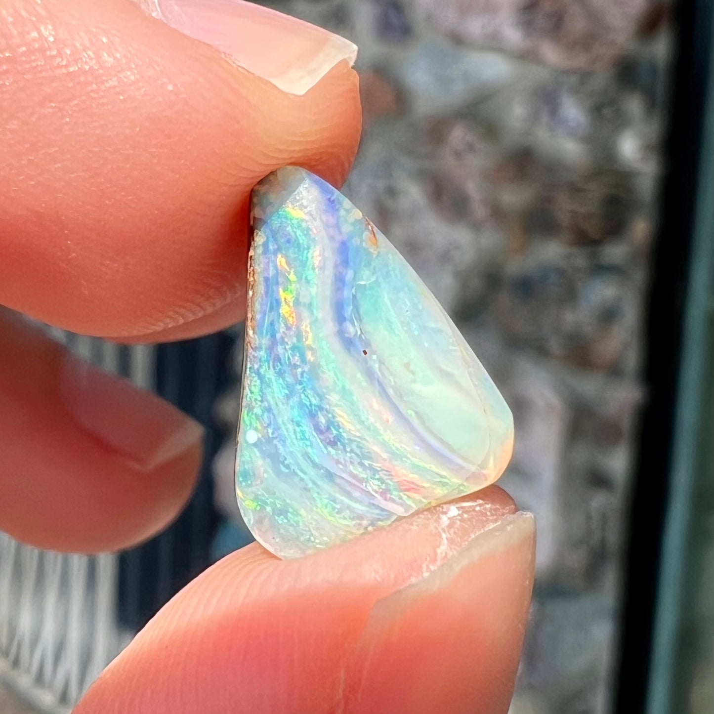 A loose, freeform boulder opal stone from Quilpie, Australia. The opal has a fissure inclusion.