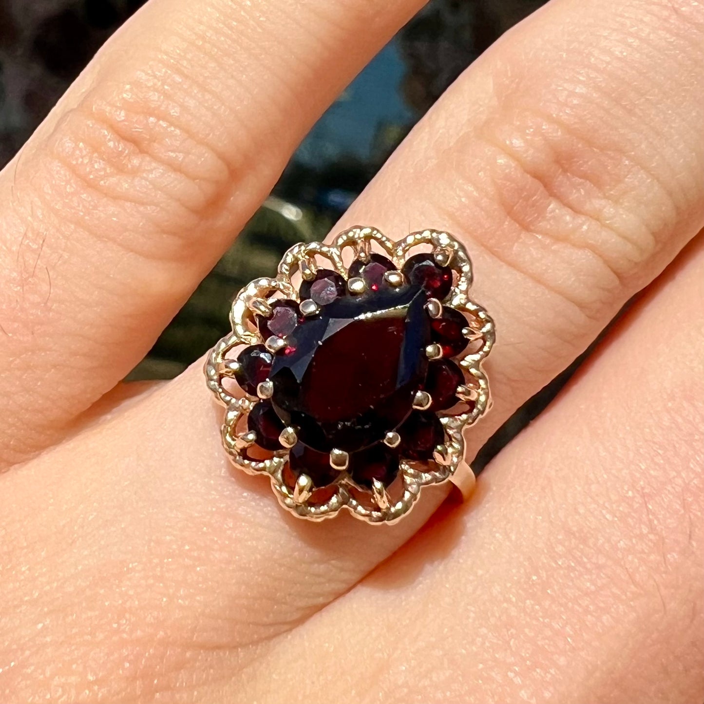 A vintage, 1940's style yellow gold ring set with a pear shaped almandine garnet. A halo of round garnets surround the center stone.