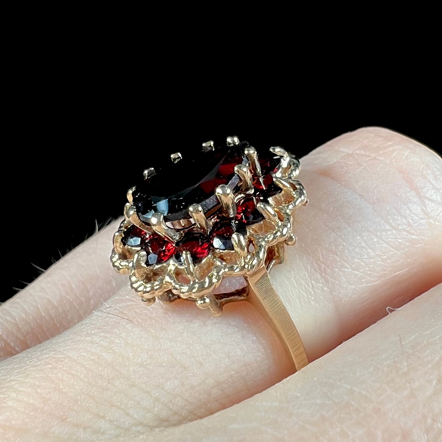 A vintage, 1940's style yellow gold ring set with a pear shaped almandine garnet. A halo of round garnets surround the center stone.