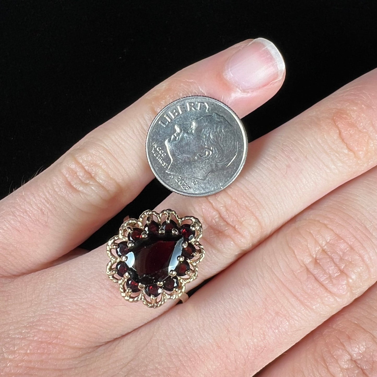 A vintage, 1940's style yellow gold ring set with a pear shaped almandine garnet. A halo of round garnets surround the center stone.