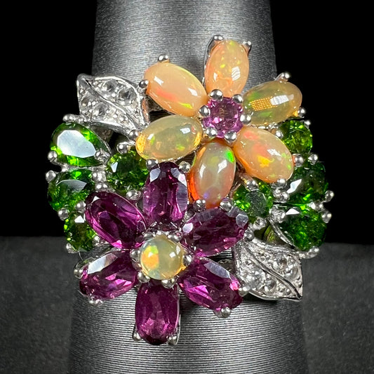 A ladies' gemstone flower design cluster ring set with Ethiopian fire opals, chrome diopsides, rhodolite garnets, and white topaz stones.