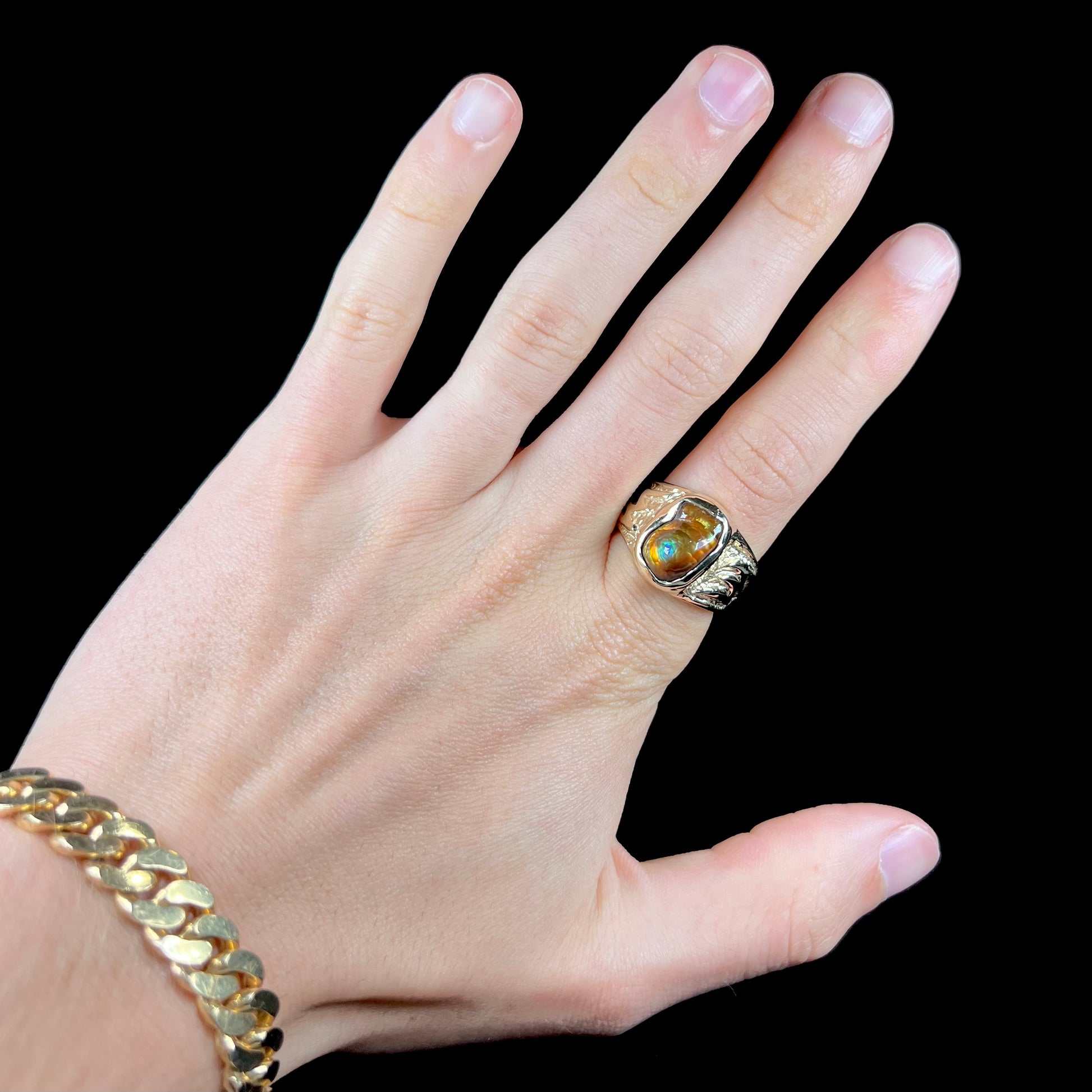 A man's yellow gold solitaire ring set with a freeform shaped Mexican fire agate stone.  The stone has a purple bull's eye pattern.