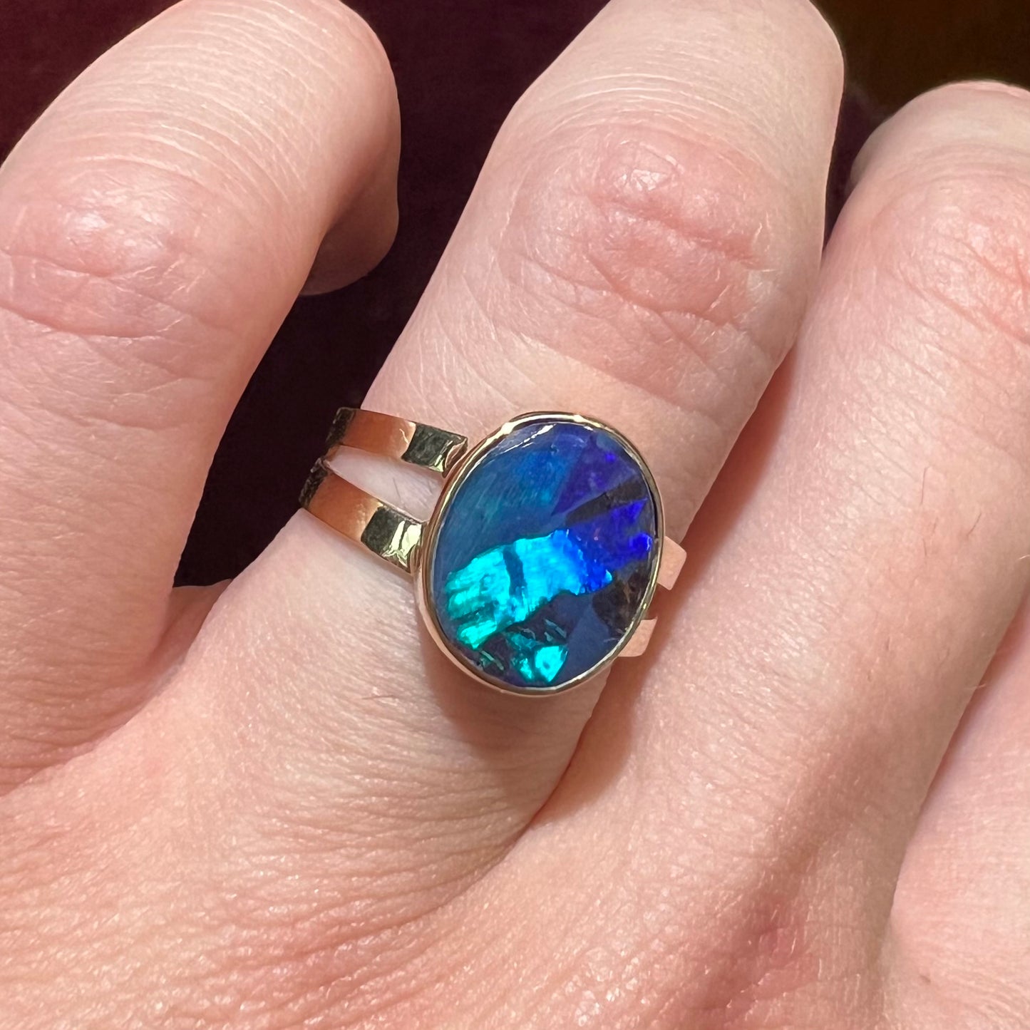 A ladies' split shank natural, Lightning Ridge, Australian black opal solitaire ring in yellow gold.