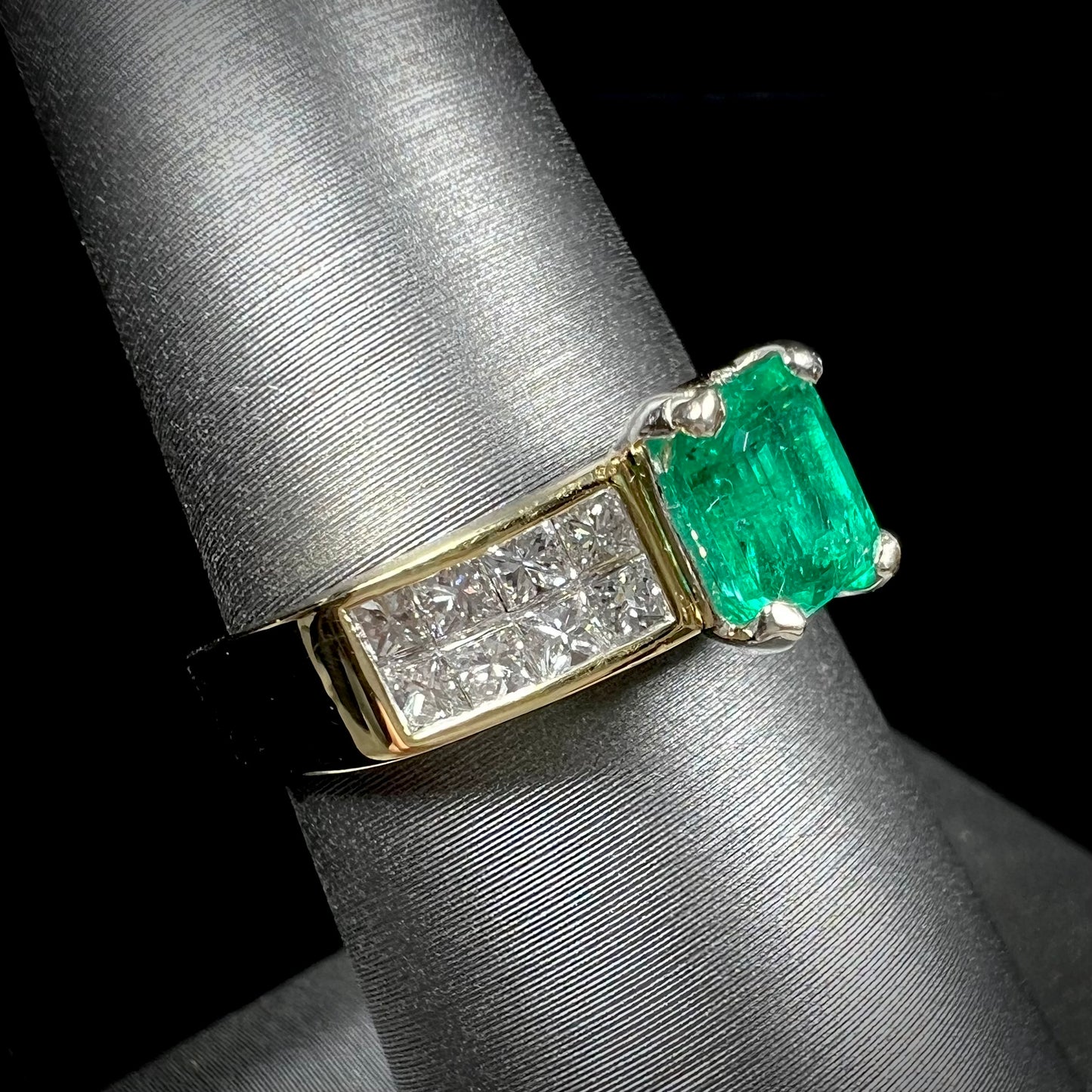 An 18 karat yellow gold ladies' emerald ring, channel set with princess cut diamonds.