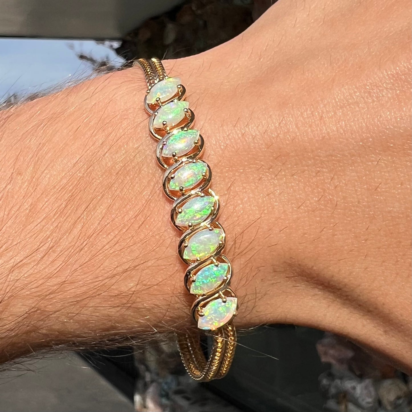 A ladies' yellow gold bracelet prong set with eight natural, marquise cabochon cut opals.