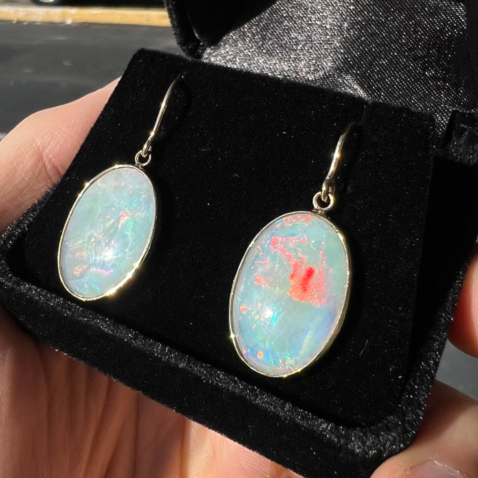 A pair of yellow gold earrings bezel set with oval cabochon cut natural opal stones.
