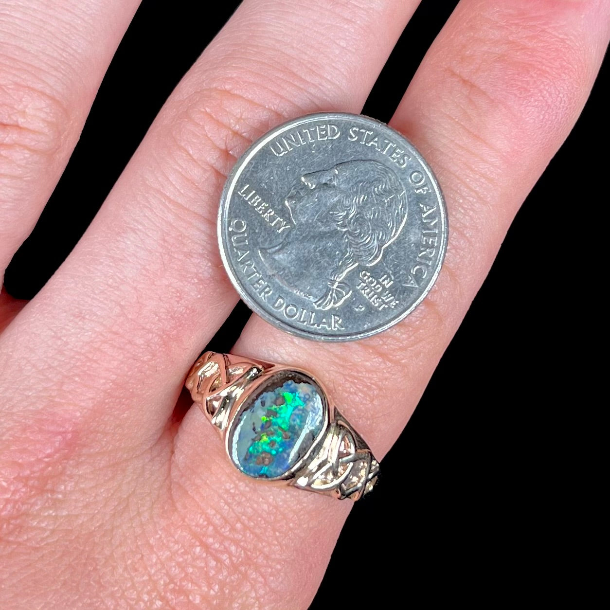 A unisex Celtic style natural boulder opal ring cast in yellow gold. The opal shines green and blue.