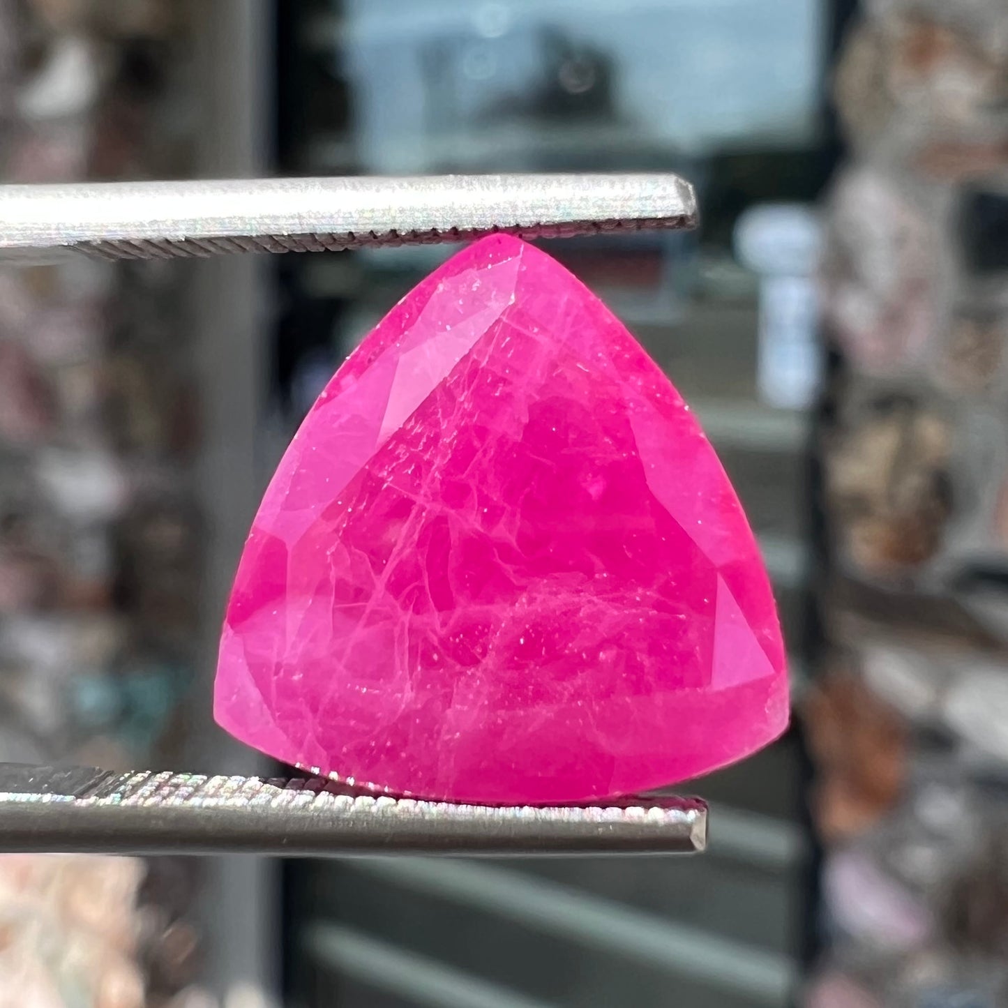 A loose, faceted trillion cut, natural, commercial grade ruby gemstone. The stone is purplish red color.