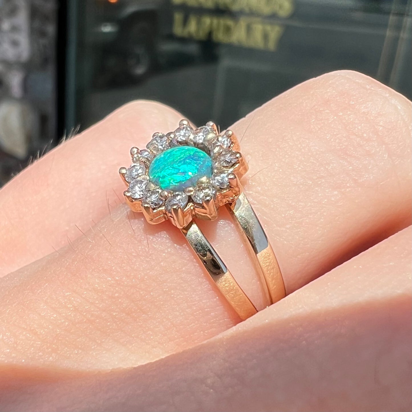 A ladies' round cut black opal and diamond halo ring. The ring is yellow gold and has a split shank.