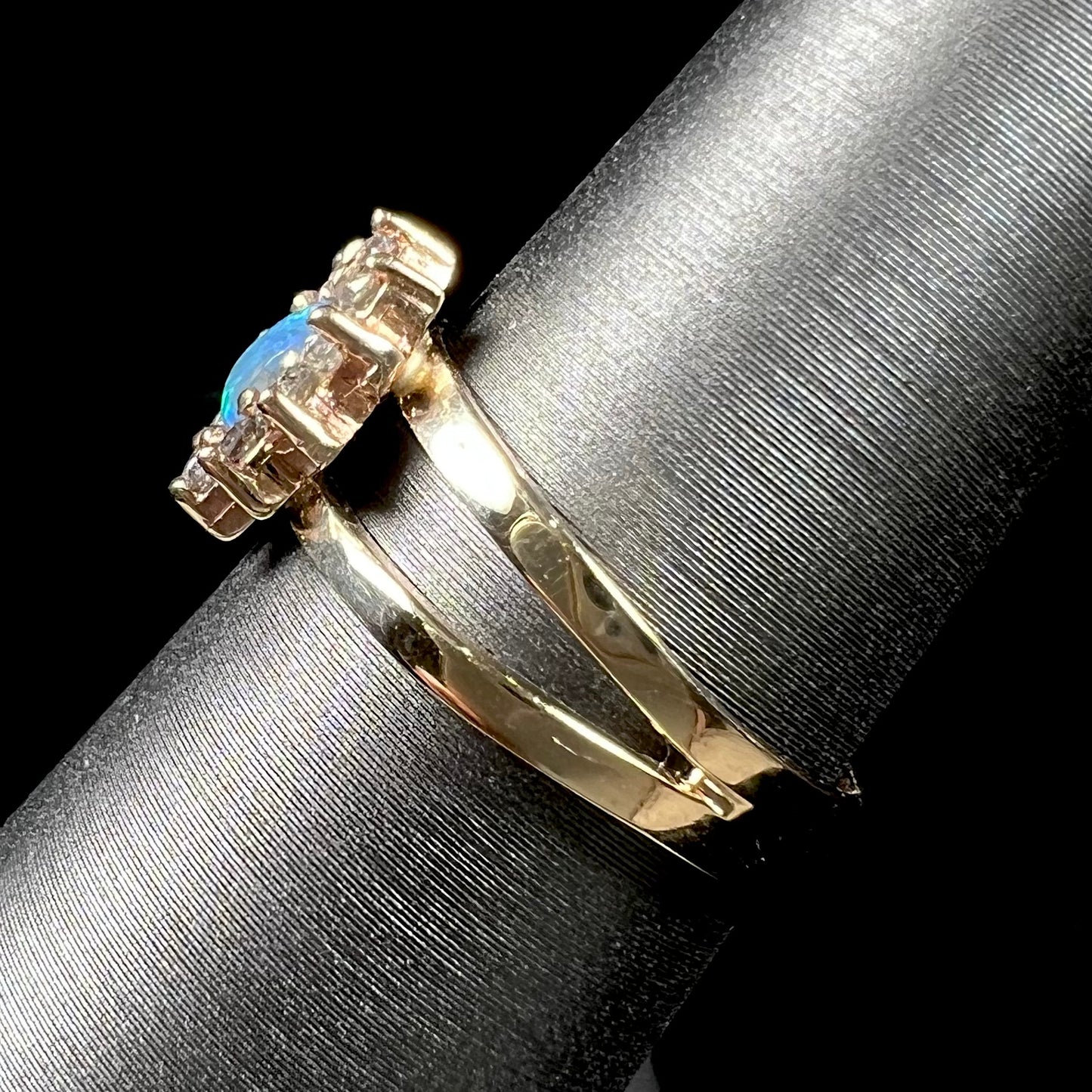 A ladies' round cut black opal and diamond halo ring. The ring is yellow gold and has a split shank.