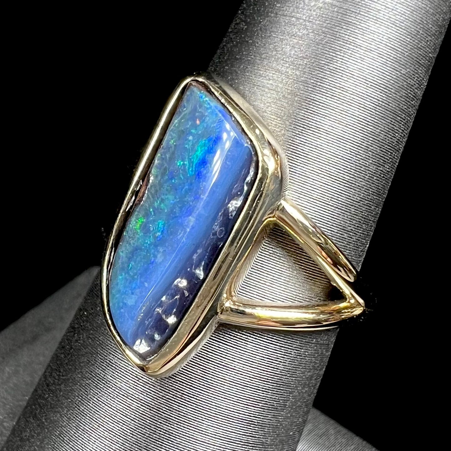 A ladies' split shank gold ring bezel set with a natural, Australian black boulder opal.