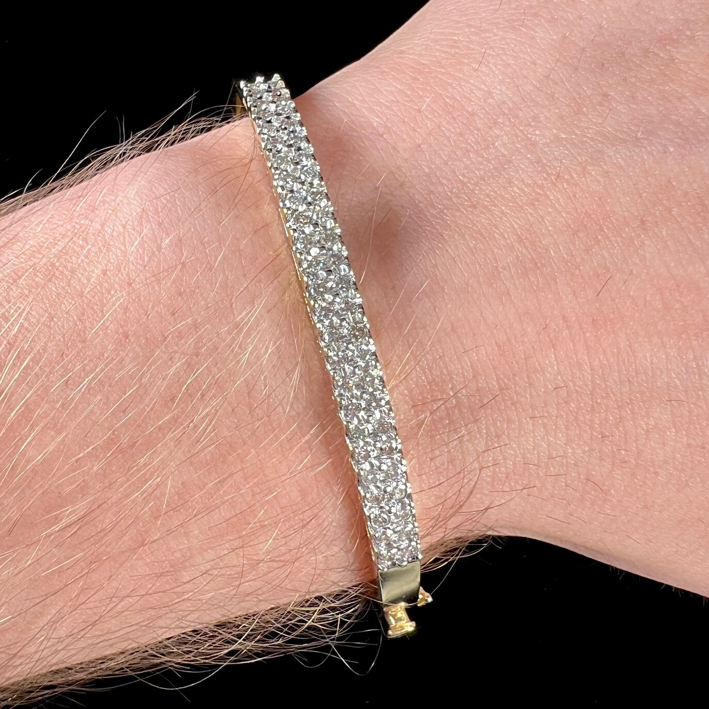 A ladies' hinged yellow gold bangle bracelet set with 50 Standard Round Brilliant Cut diamonds.